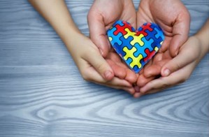 Four hands holding a heart together