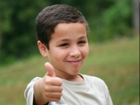 Empowerment program picture A young boy with a smile on his face, giving a thumbs up